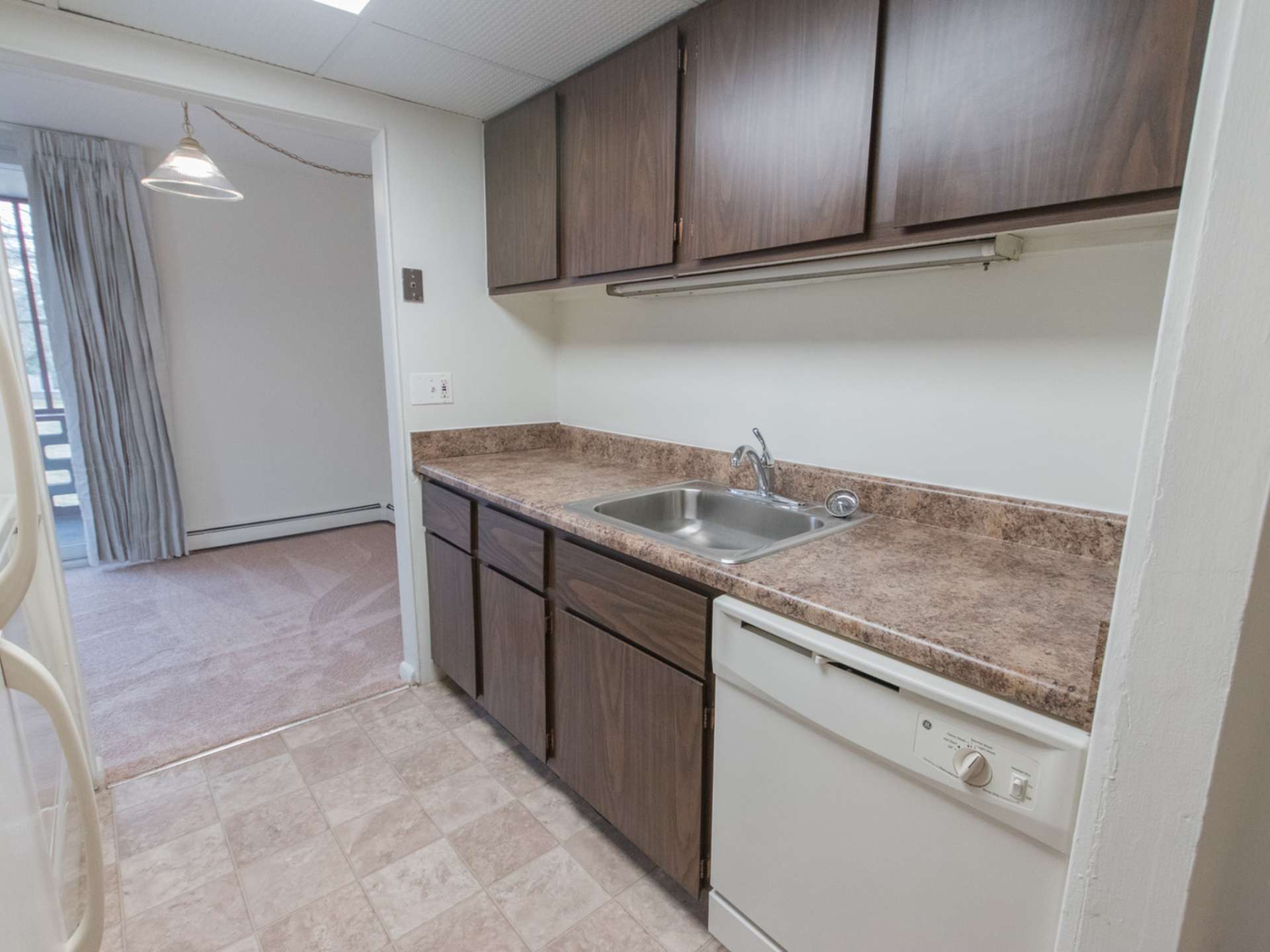 Kitchen area with white appliances and wooden cabinets at Lake Club Apartments.