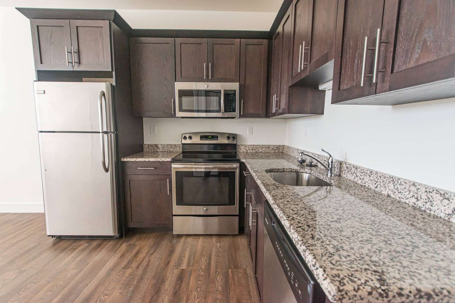 Kitchen with marbled countertops and stainless steel appliances at Magnolia Place Apartments.