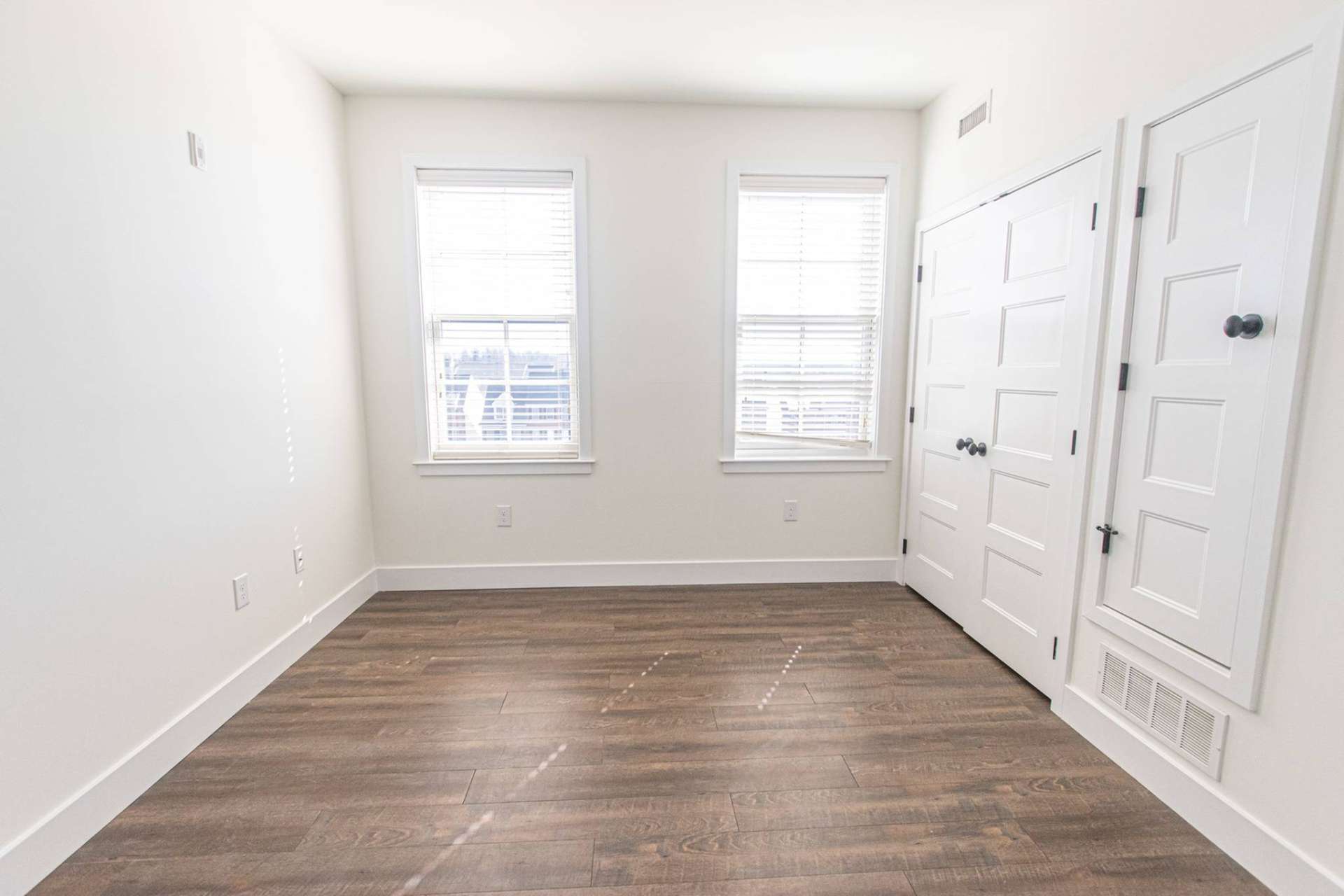 Bedroom with hardwood-style flooring, a closet, and 2 windows.