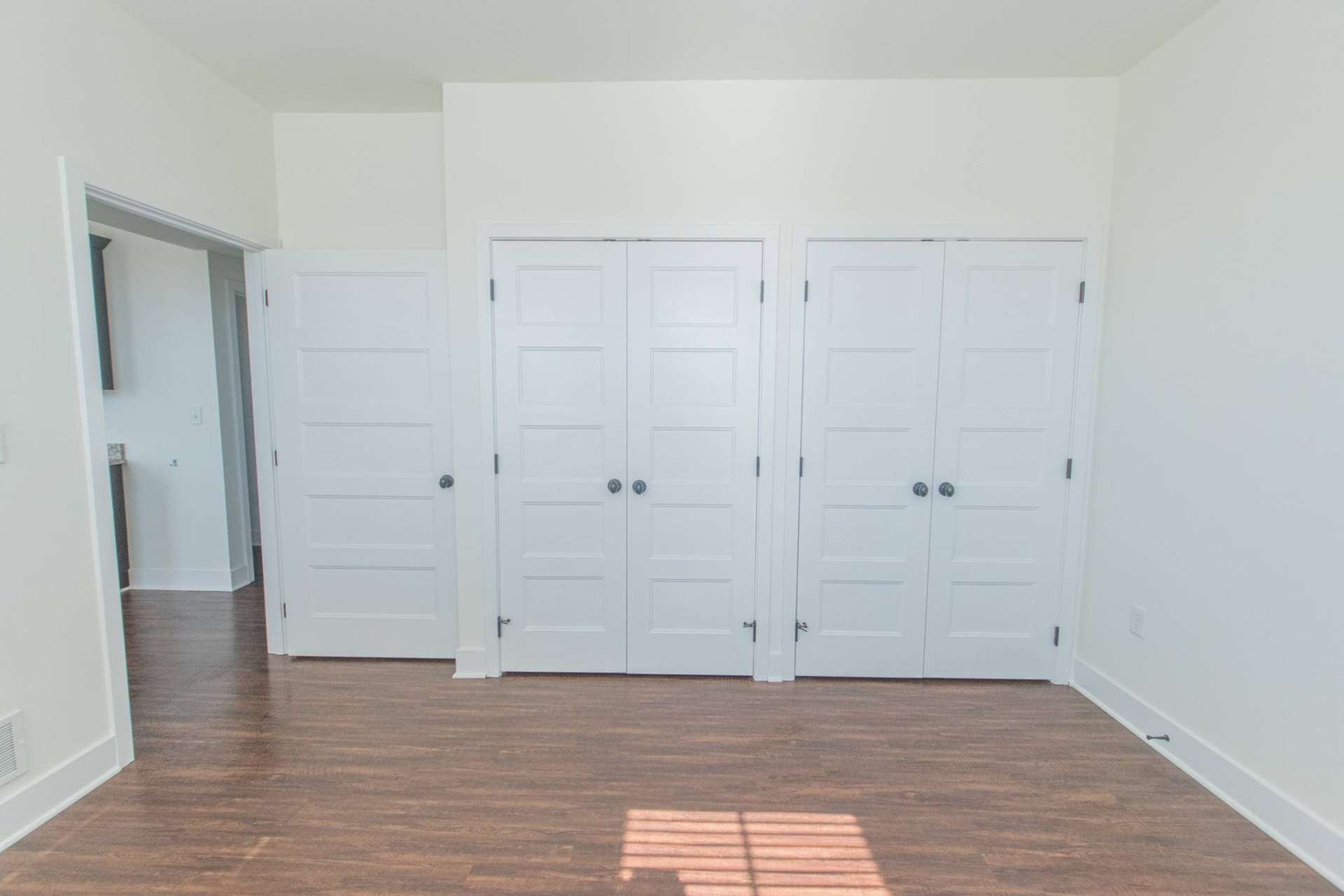 Bedroom with wooden floors and two closets.