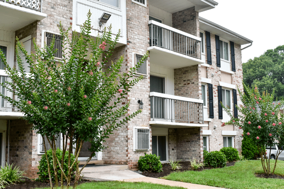 The exterior of an apartment building at fitted with a paved walkway, and a lawn