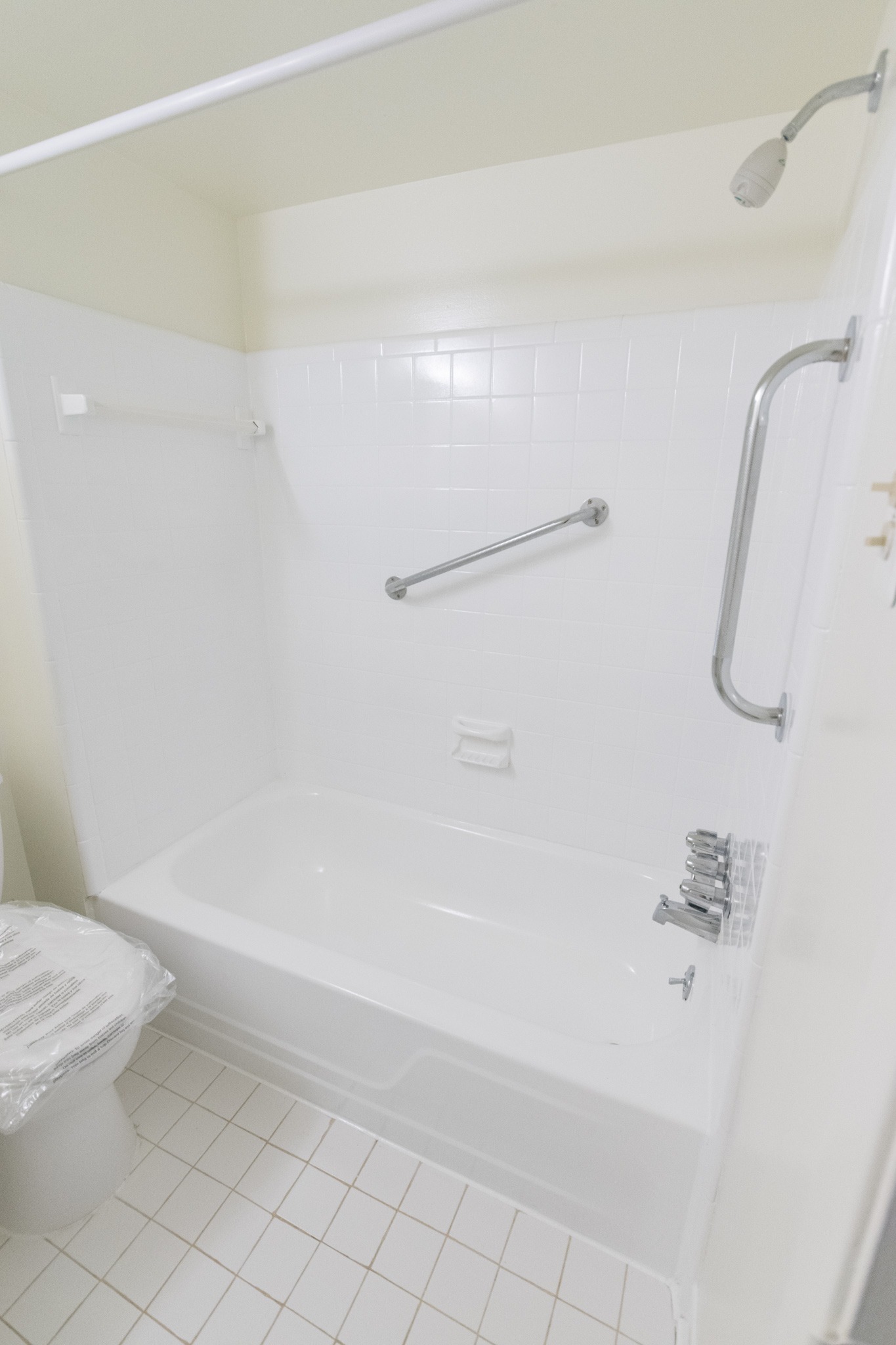Willow Run Apartments white tiled bathroom with bath and shower