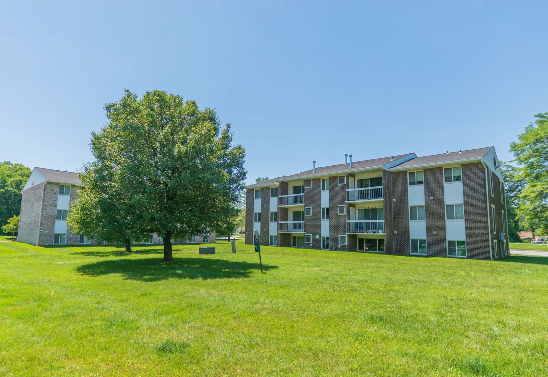 Exterior of an apartment building at Chesapeake Village apartments, fitted with a lawn, and trees