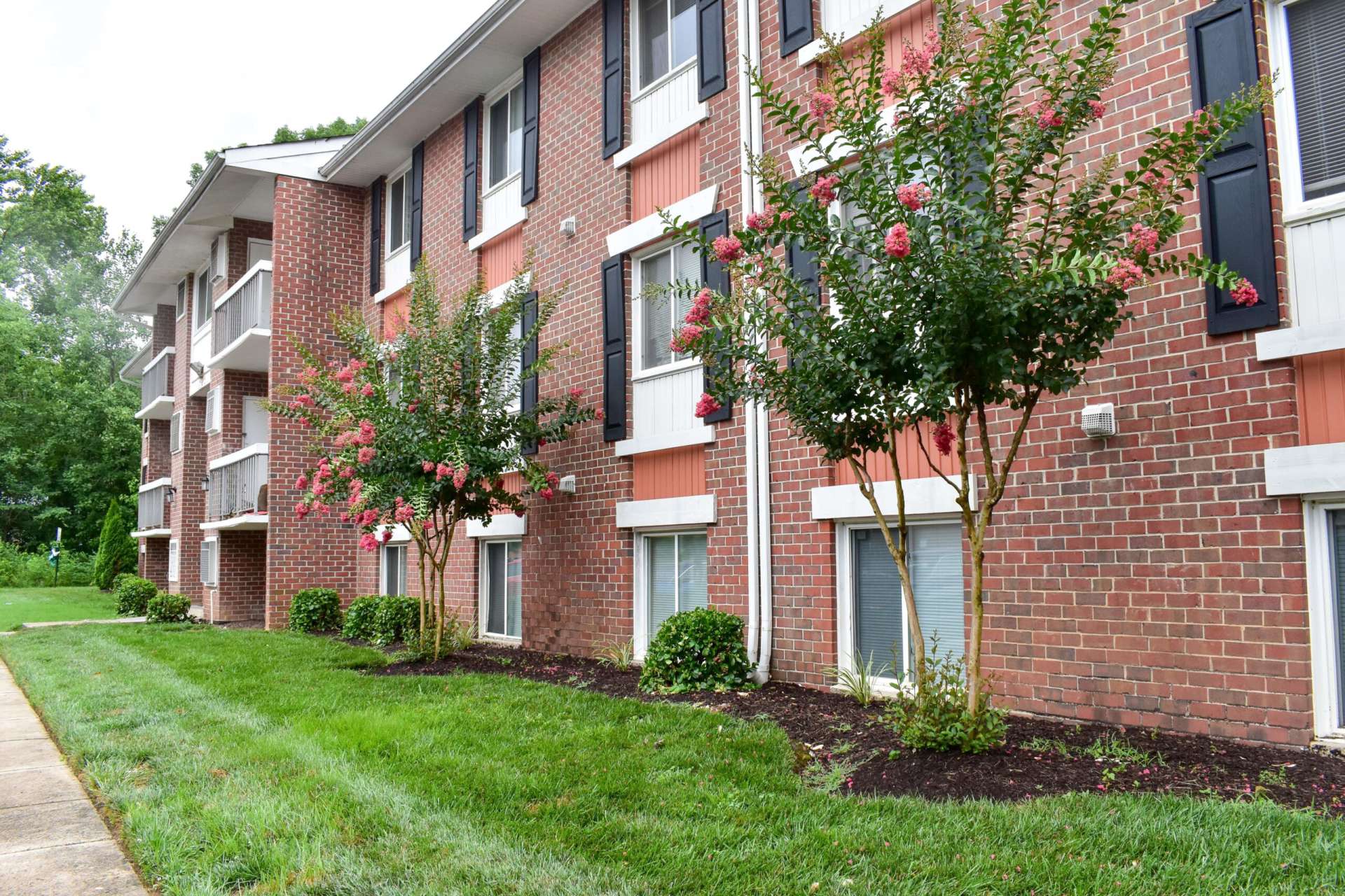 The exterior of an apartment building at Chesapeake Village apartments, fitted with a lawn, and flowers
