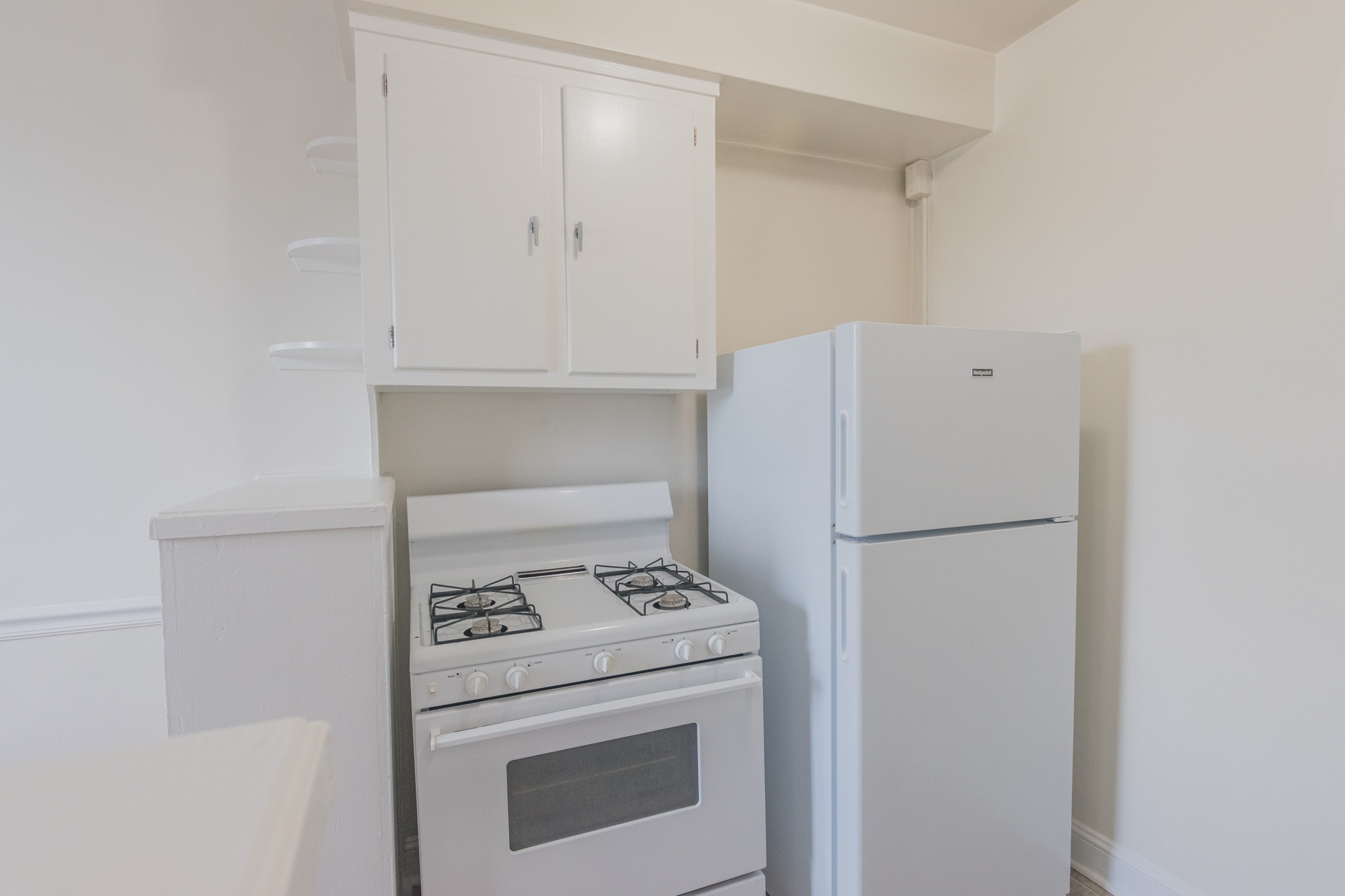 Kitchen area of an apartment, fitted with a stove, a fridge, and spacious cabinets