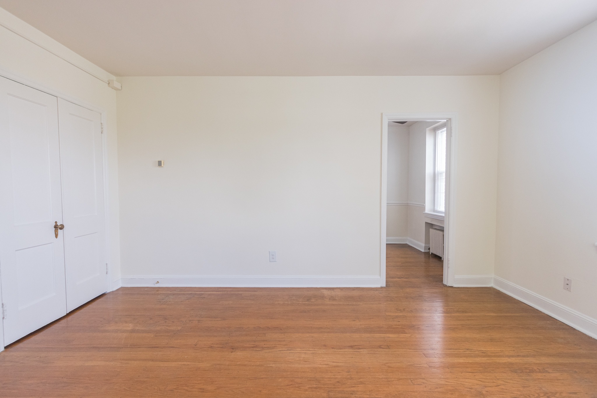 Bedroom area of an apartment unfurnished, fitted with wooden flooring, a closet, and a high ceiling