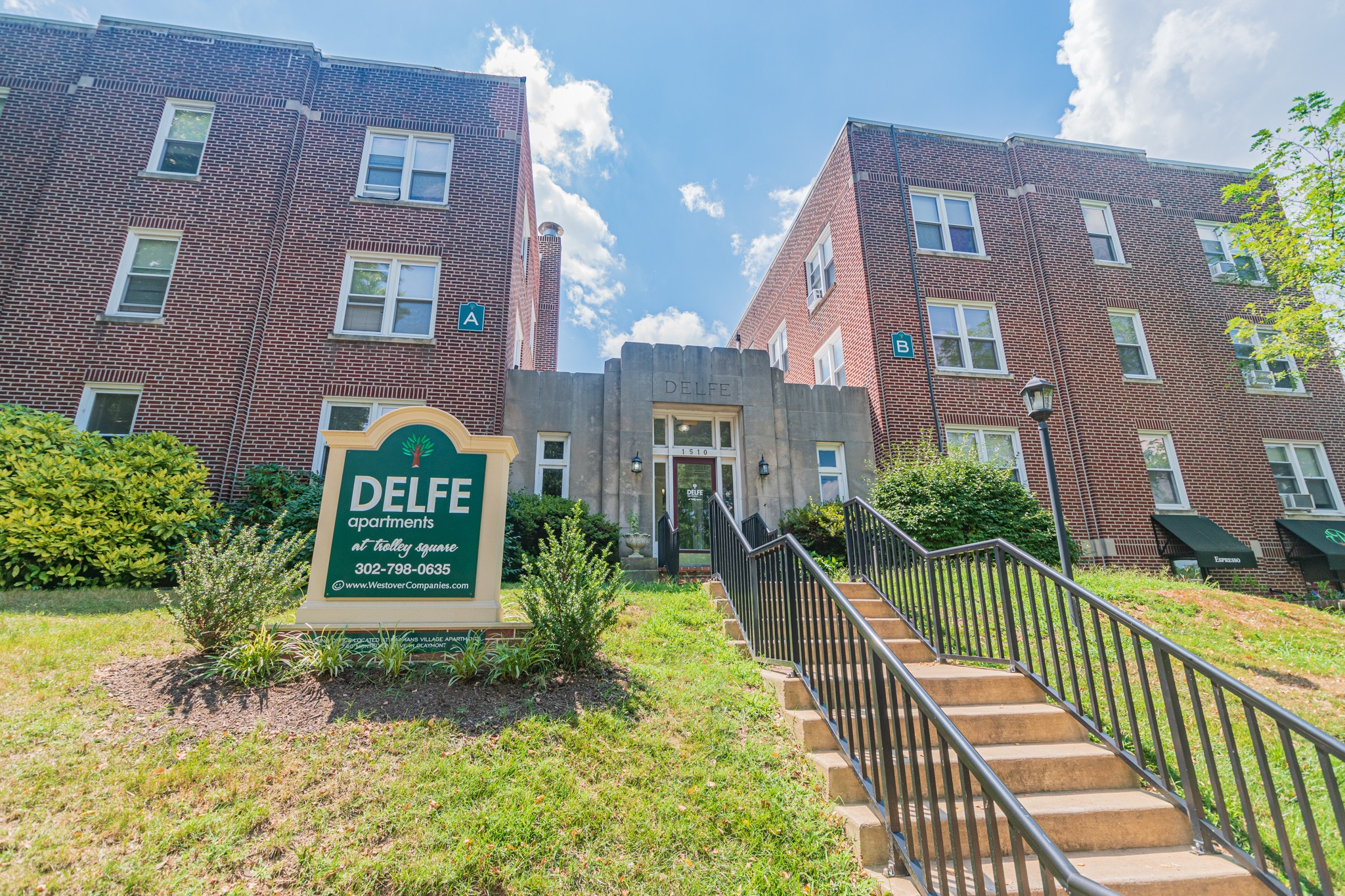 Entrance to the leasing office at Delfe apartments, fitted with steps with railing, and a welcome sign