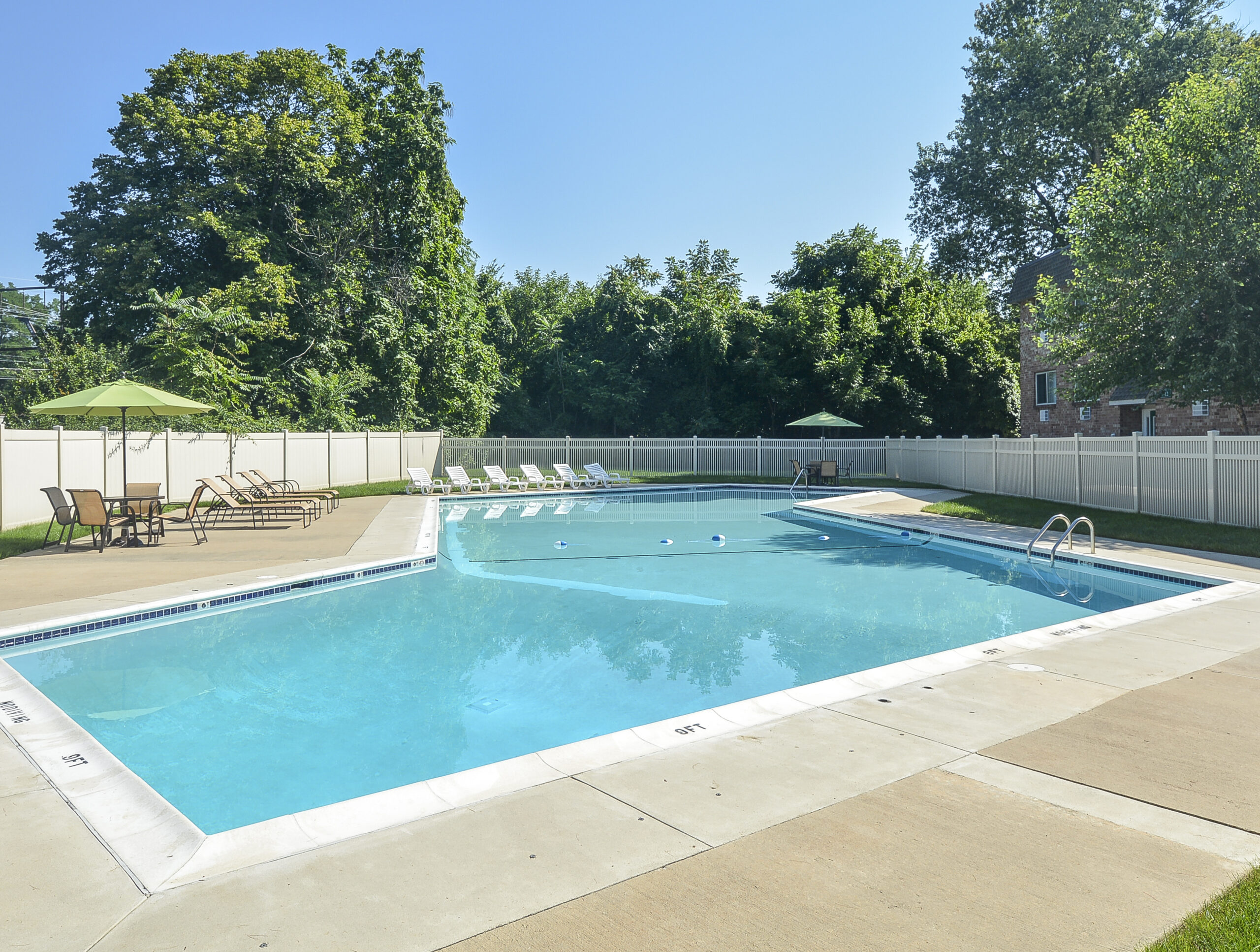 Swimming pool area of our community, fitted with a sun deck, concrete flooring, and pool chairs