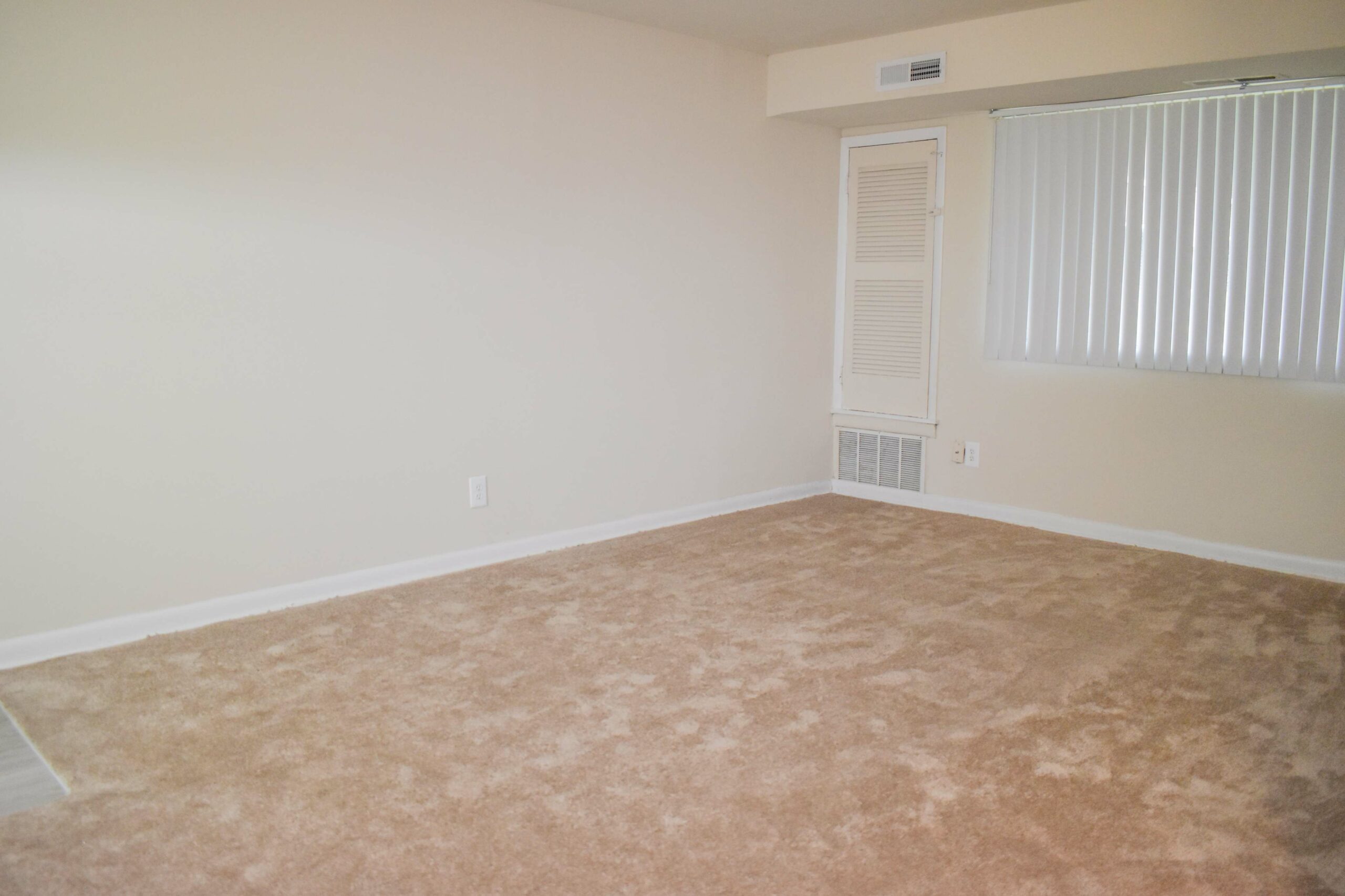 Living room area of an apartment unfurnished, fitted with carpet flooring, a ceiling fan, and a huge window