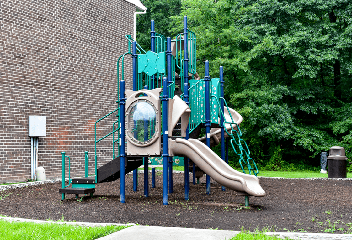 Playground area of our community, fitted with a kids slide, and a paved walkway