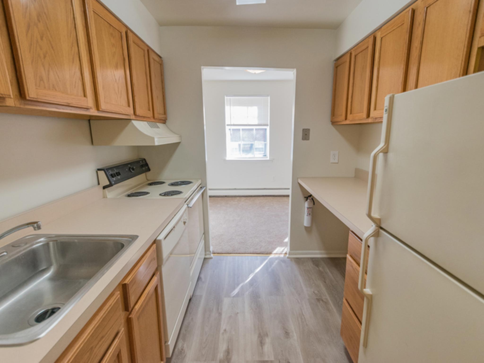 Kitchen with white appliances and light brown wooden cabinets in an apartment at Evergreen Club Apartments.