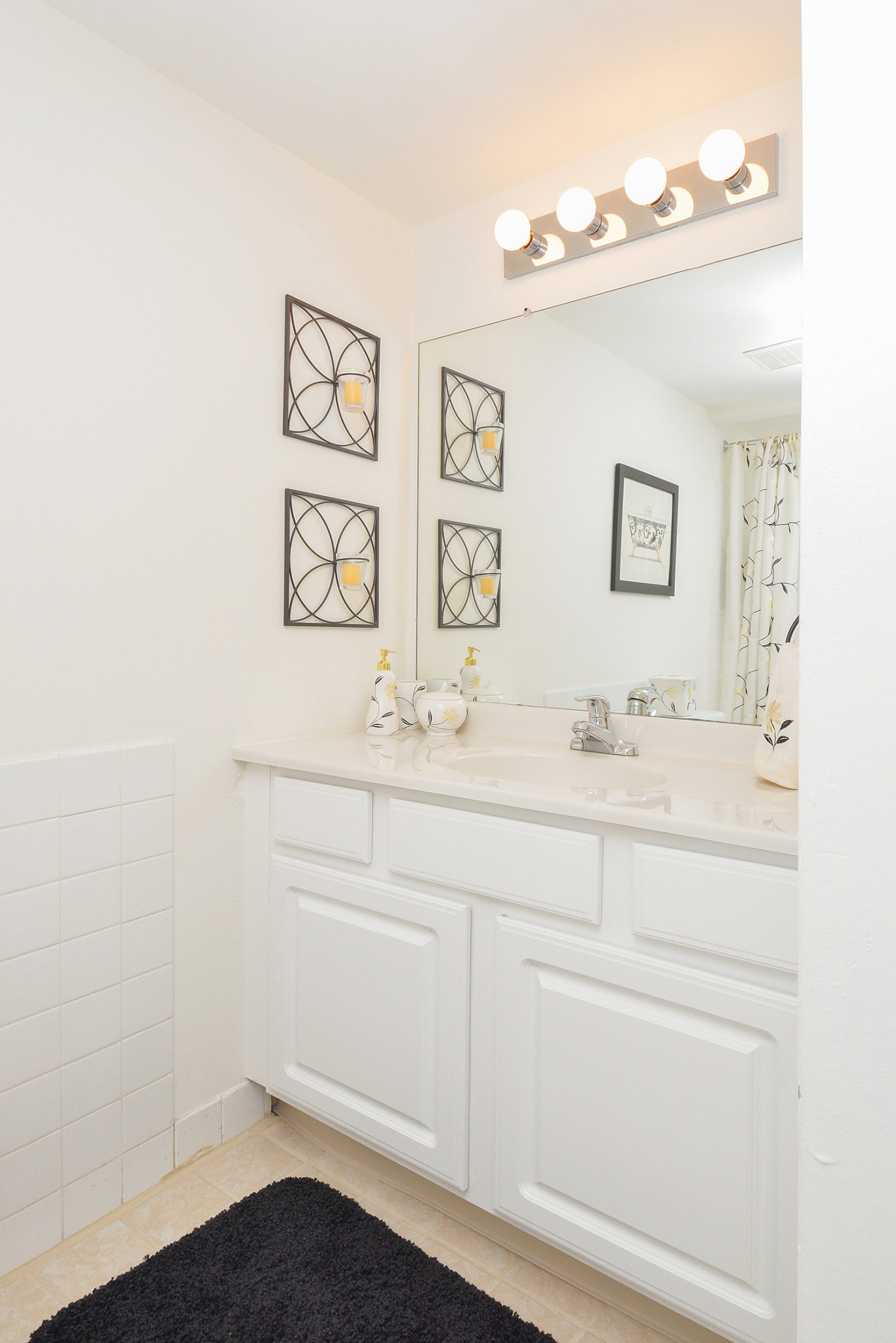 Bathroom area of an apartment is fitted with a single vanity, tiled flooring, and a high ceiling