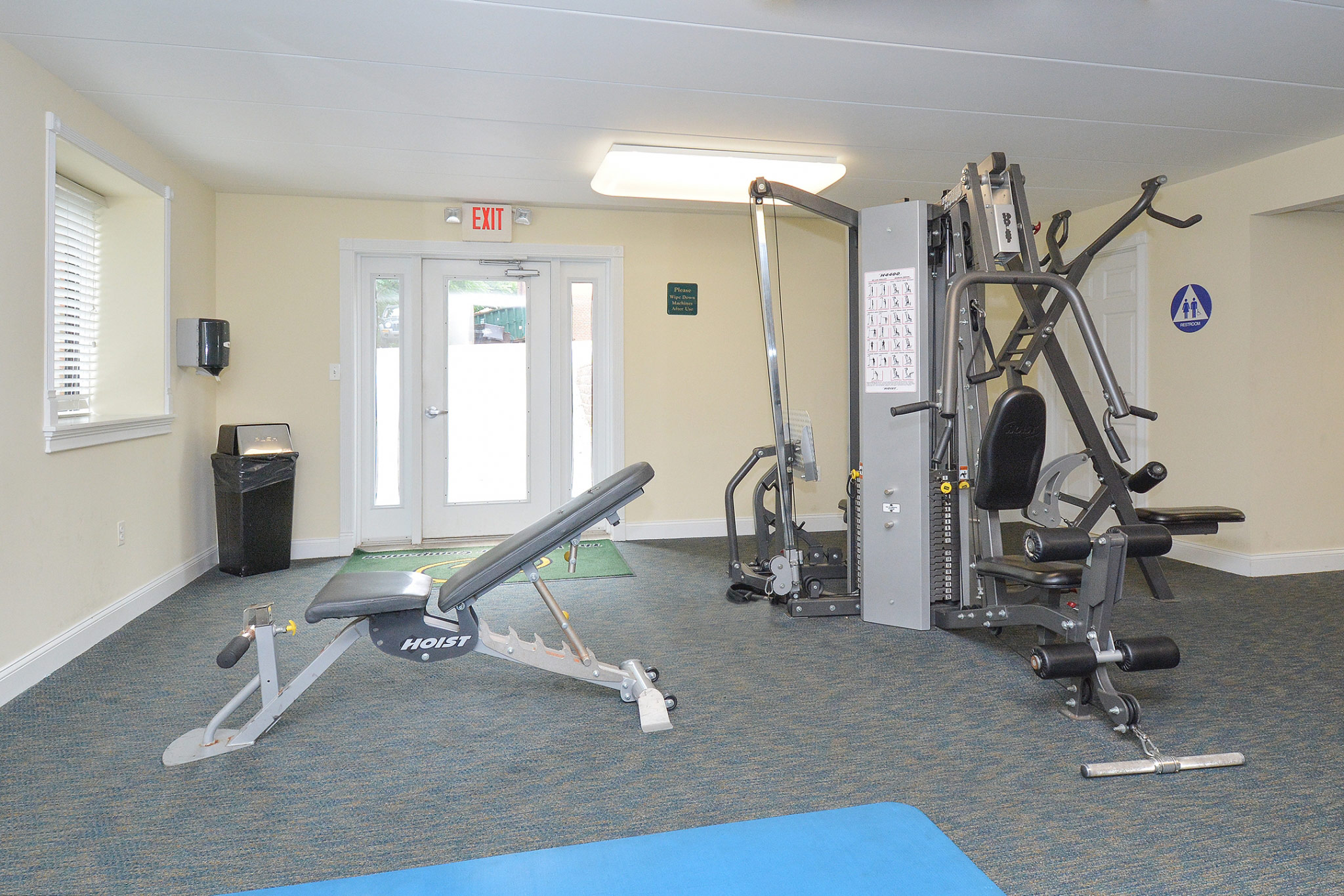 Area of our Fitness center in our community, fitted with fitness machines, soft flooring, and exit