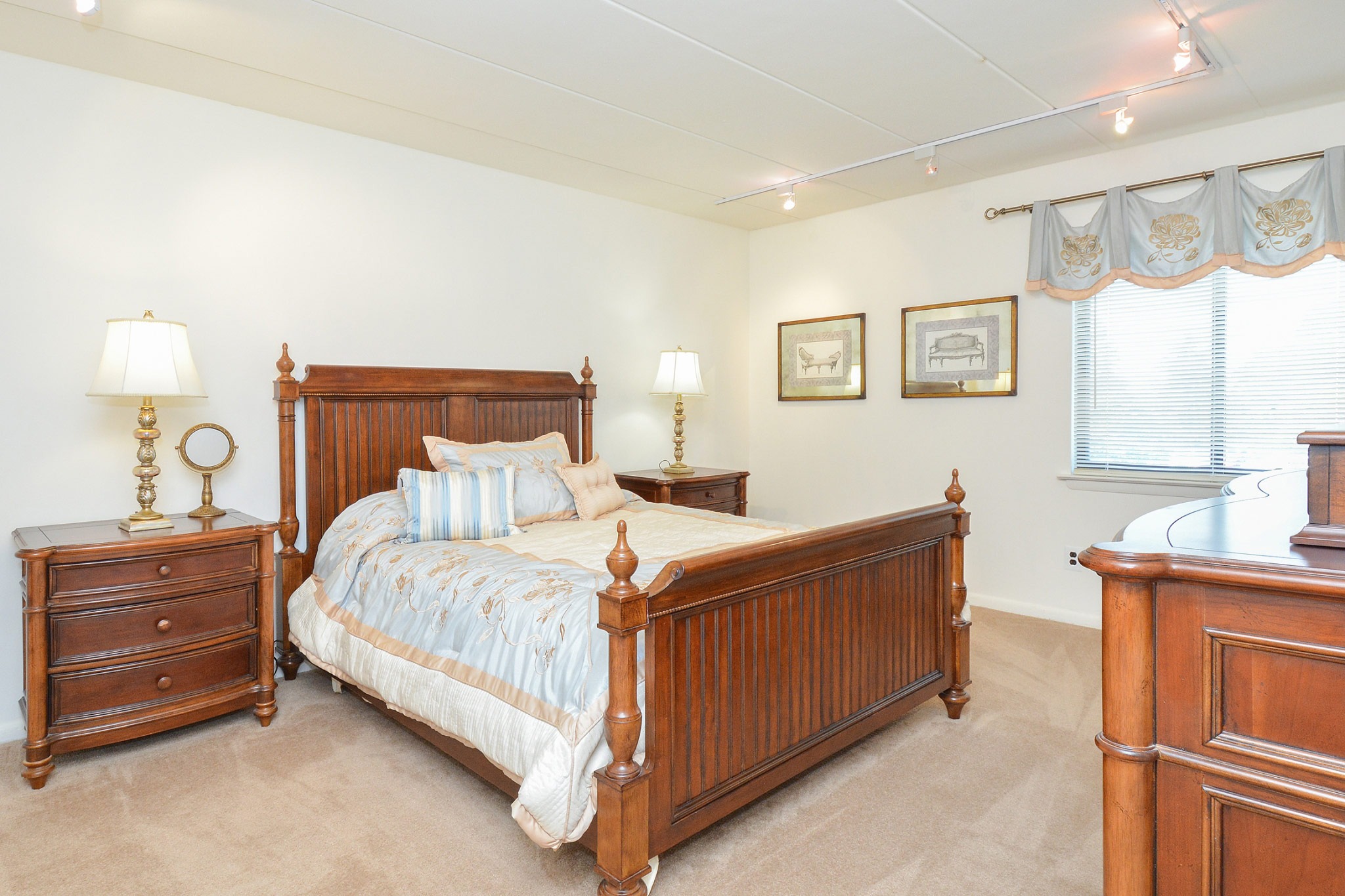 Bedroom area of an apartment is furnished with a queen size bed, a high ceiling, and two nightstands