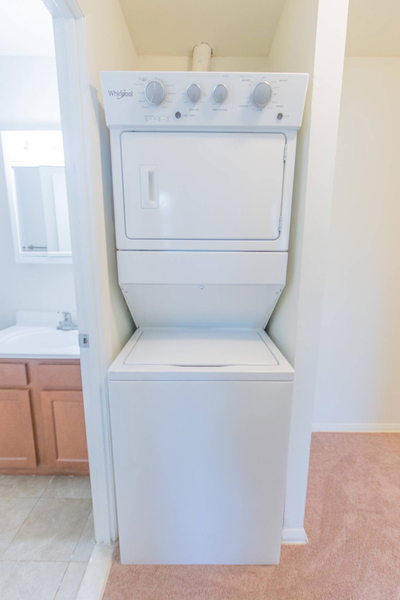 Stacked washer and dryer next to the bathroom.
