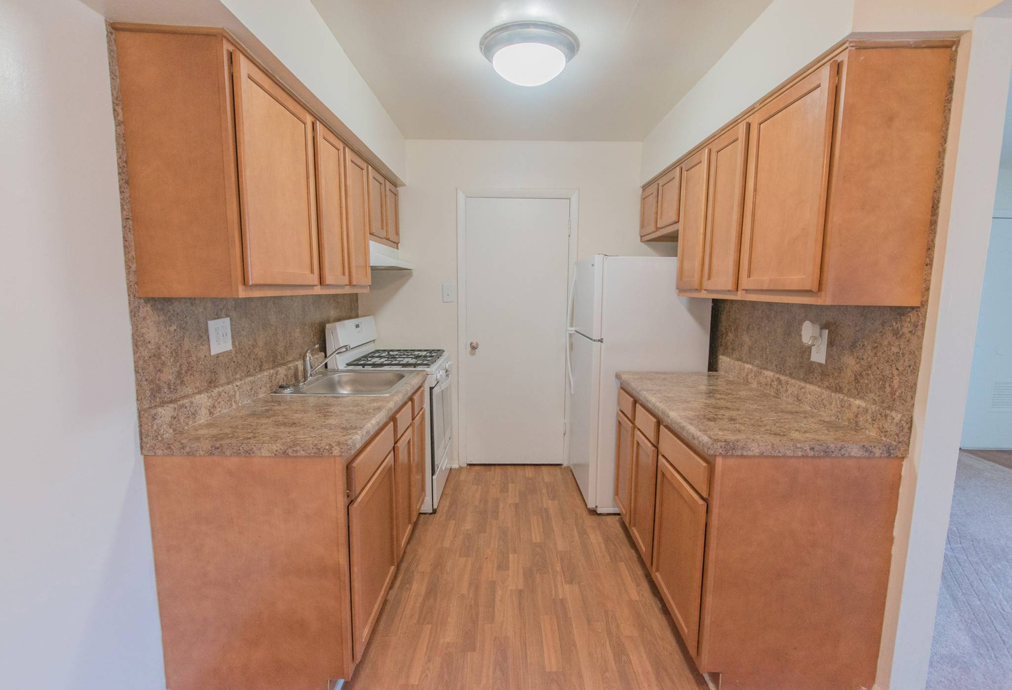 Kitchen with brown cabinets and white appliances in Middle River Townhomes.