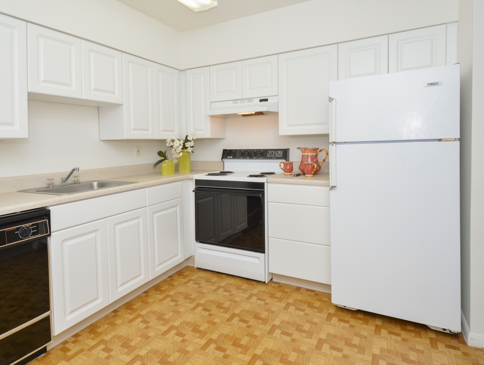A kitchen with white cabinets and black appliances at Valley Stream Apartments