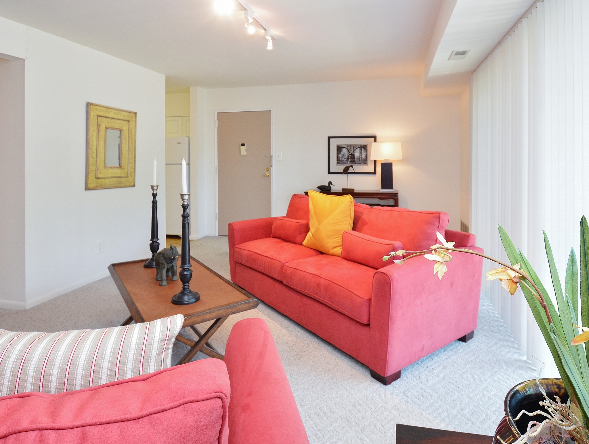 A living room with table and red couch at Valley Stream Apartments
