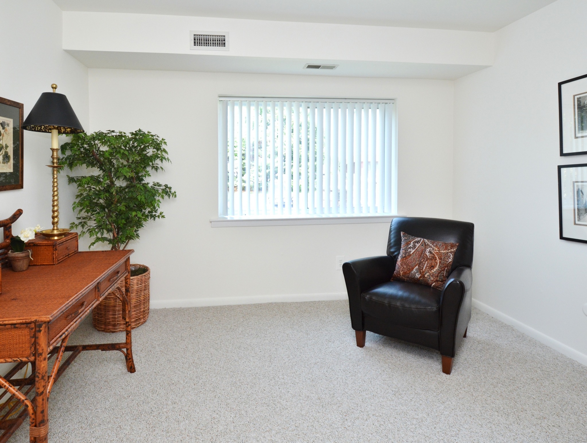 A carpeted bedroom with a chair, desk and window at Valley Stream Apartments