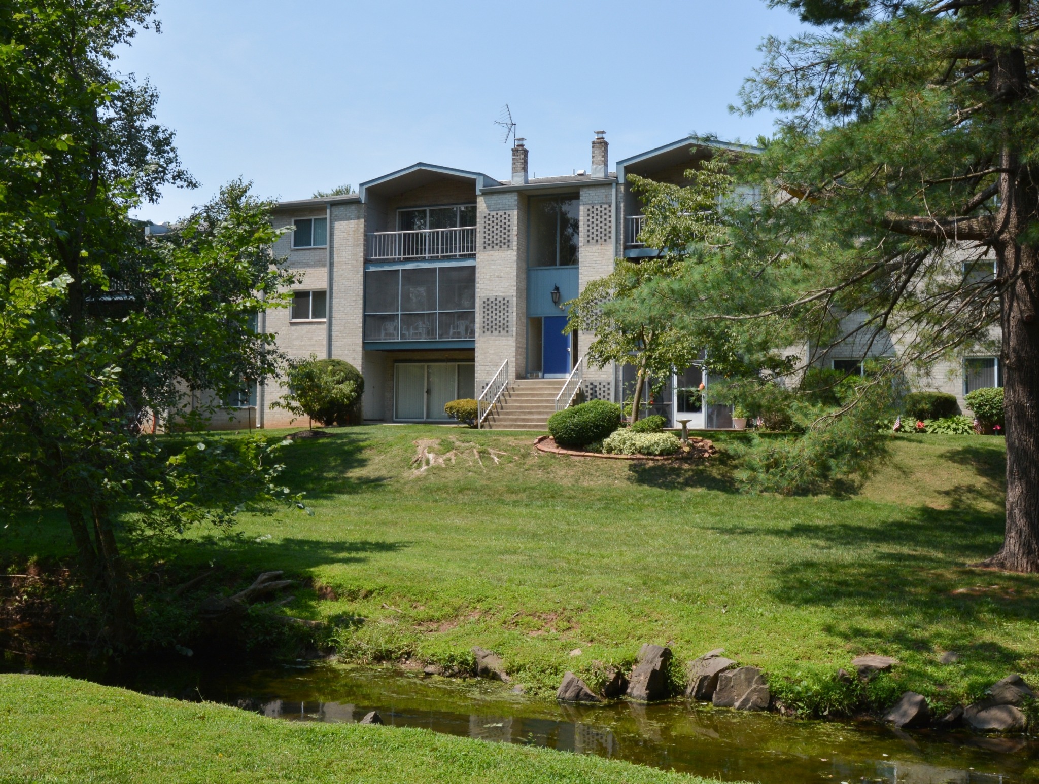 A creek and trees in front of the Valley Stream Apartments