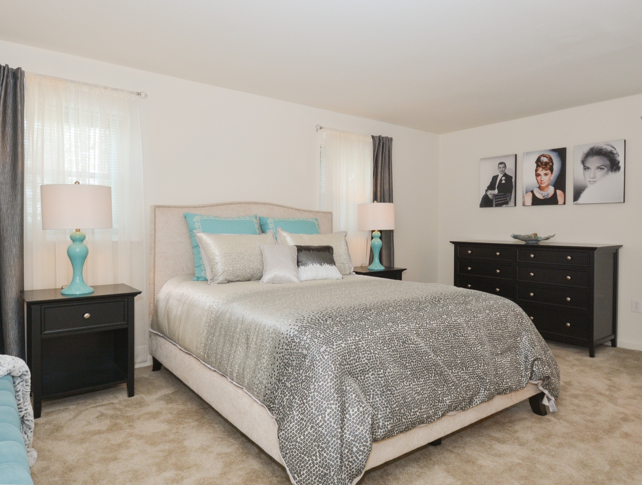 Carpeted bedroom with a bed in the middle, two nightstands, and a dresser.