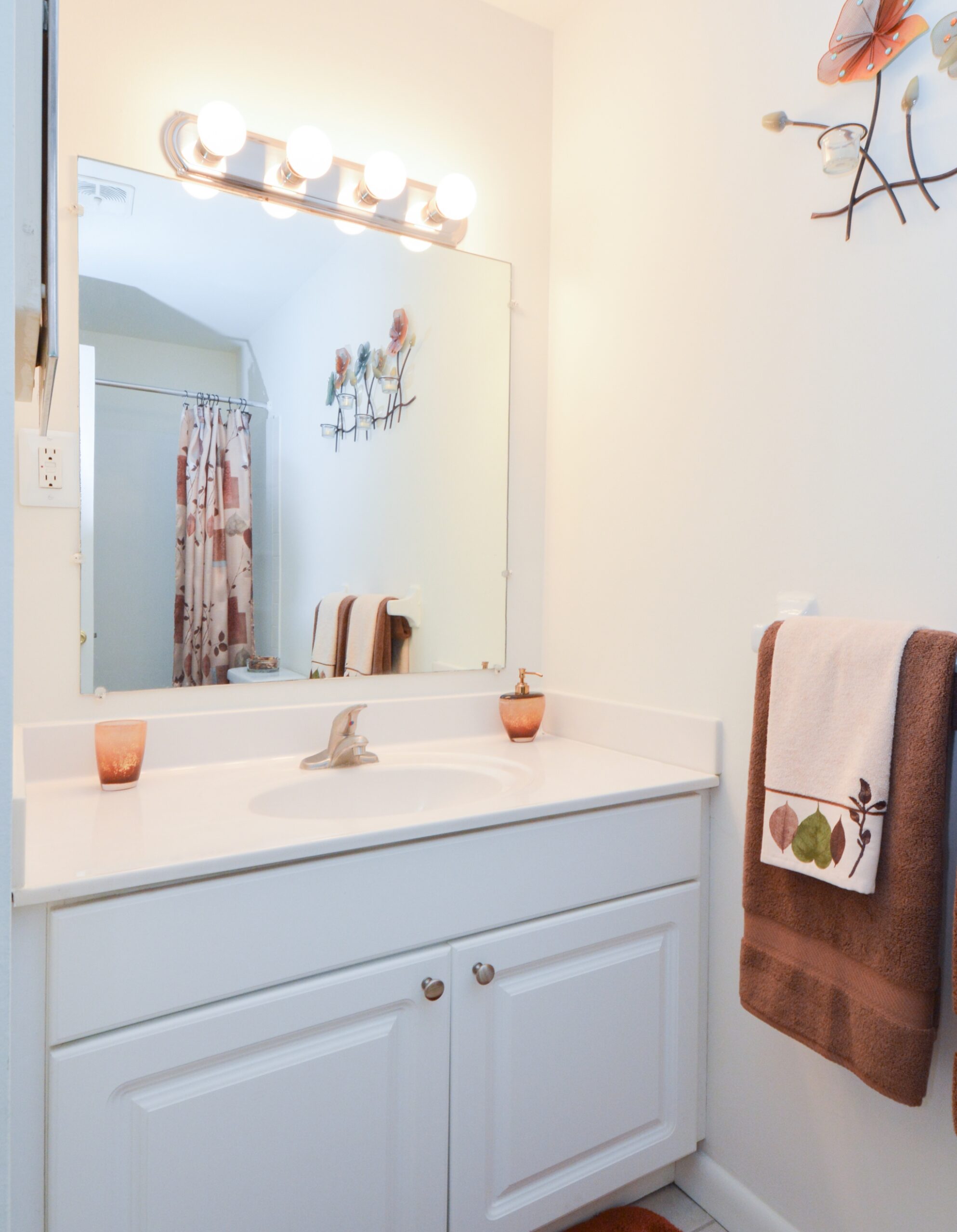 Bathroom with a large mirror, white countertops, and extra lighting above the mirror.