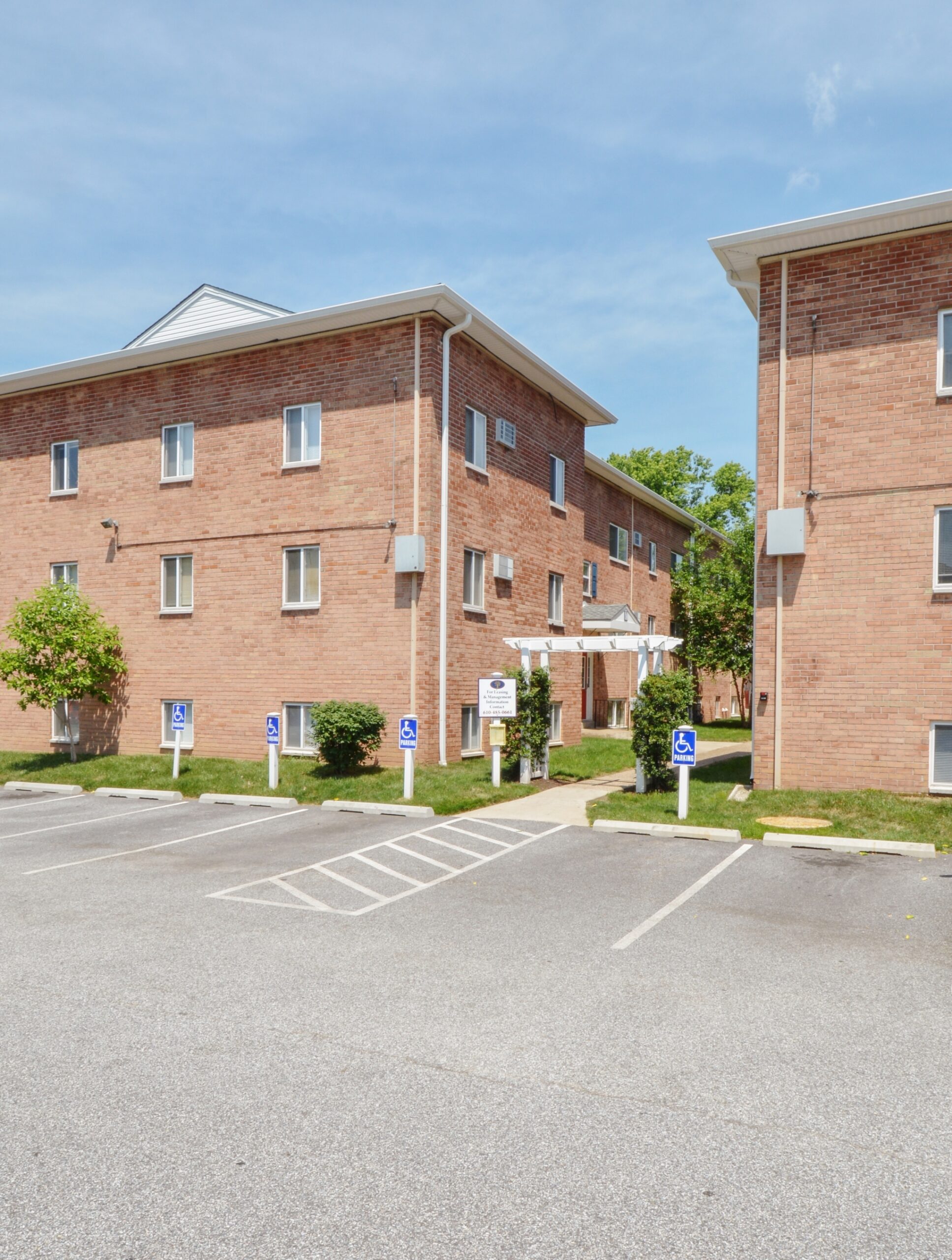 Exterior of an apartment building at Boothwyn Court apartments, fitted with parking spots, and a paved walkway