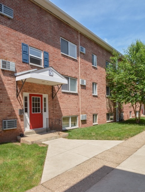Exterior of an apartment building at Boothwyn Court apartments, fitted with paved walkway, lawn, and entrance door
