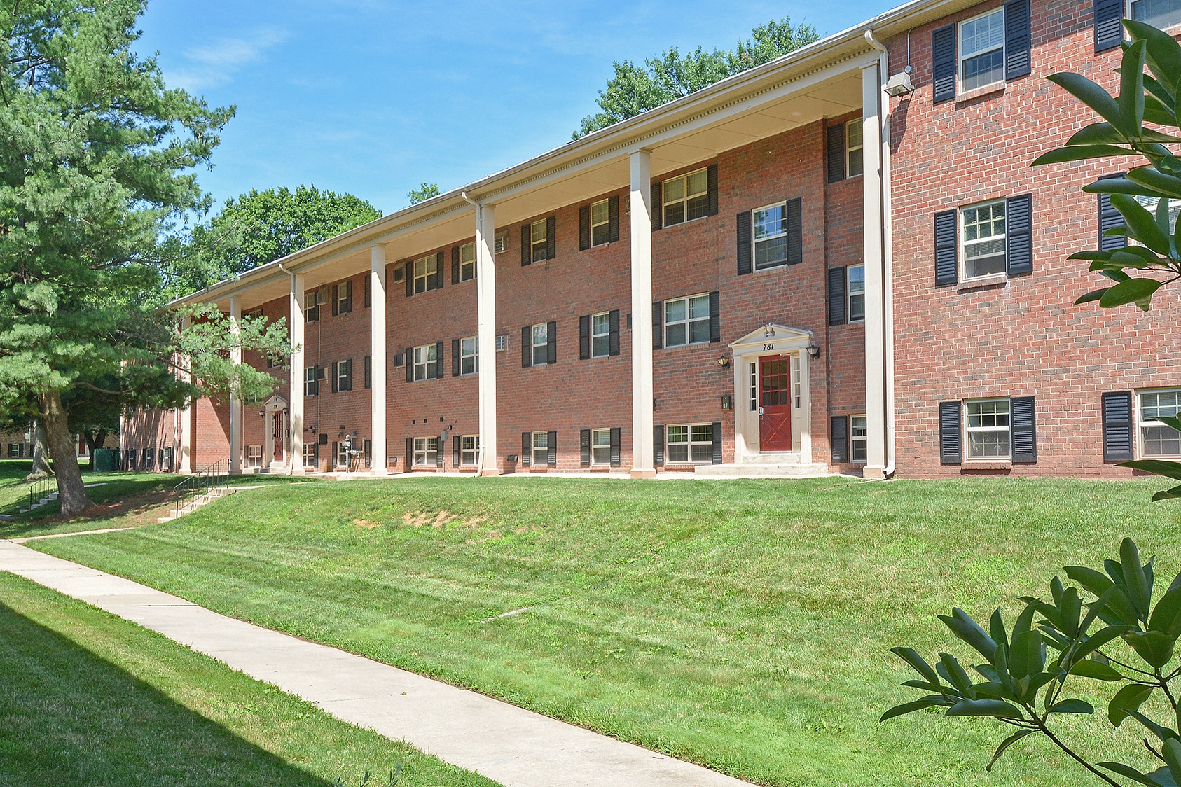 Exterior of Naamans Village Apartments with large grassy areas and sidewalks.