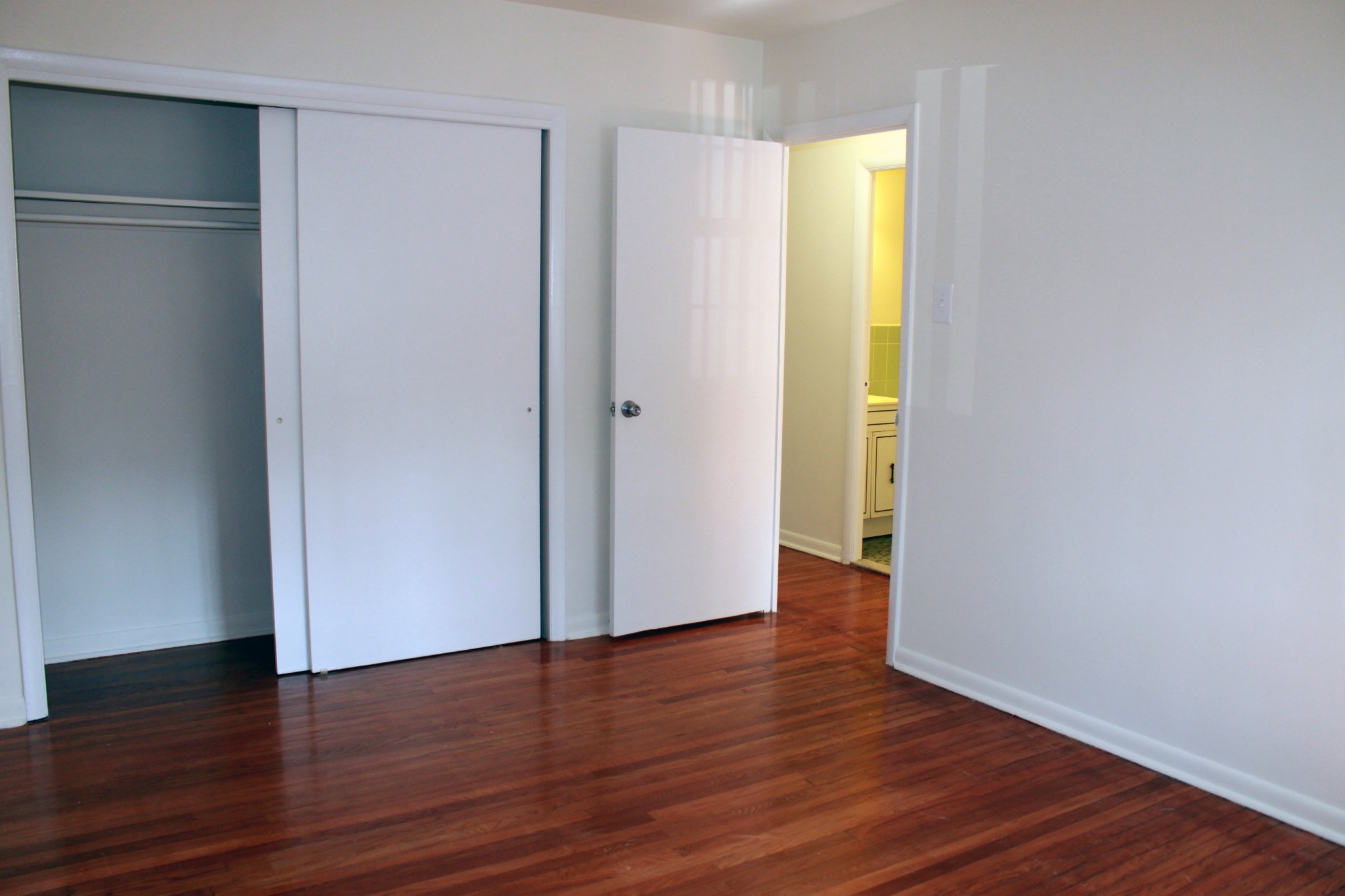 Spacious bedroom with wooden floors and a closet with sliding doors.