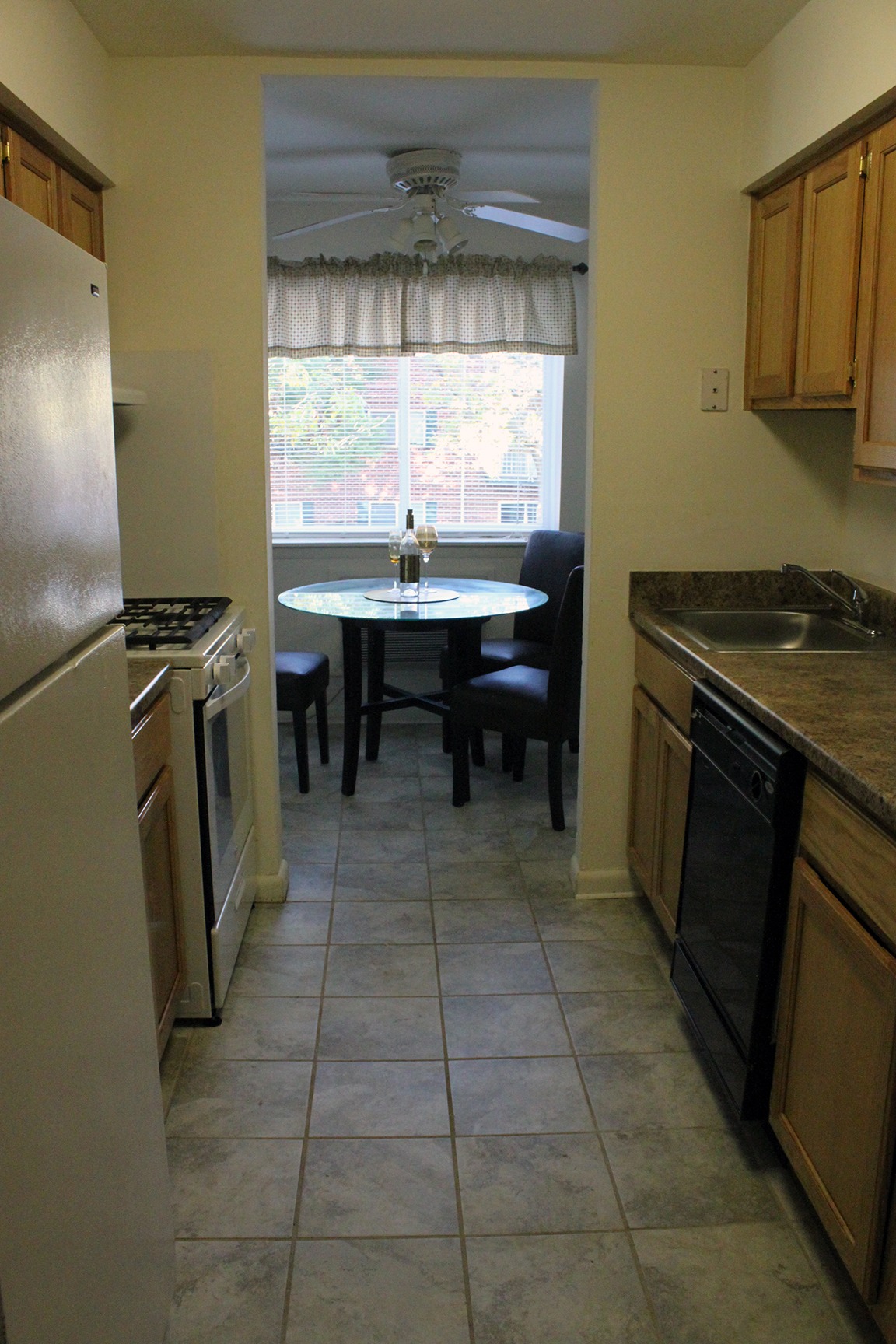 Kitchen area of an apartment, fitted with tiled flooring, spacious cabinets, and stainless steel appliances