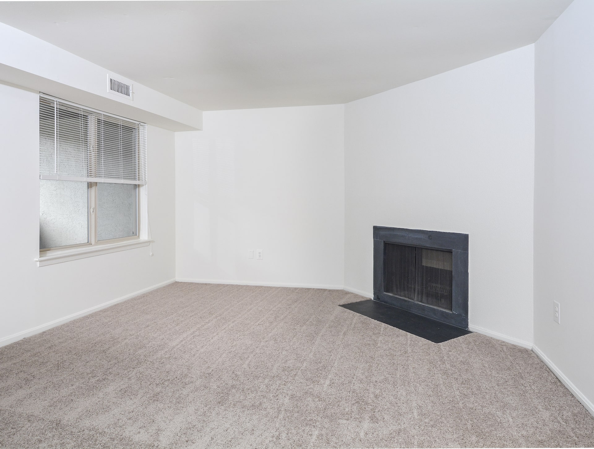 Bedroom area of an apartment unfurnished, fitted with carpet flooring, and a fire place