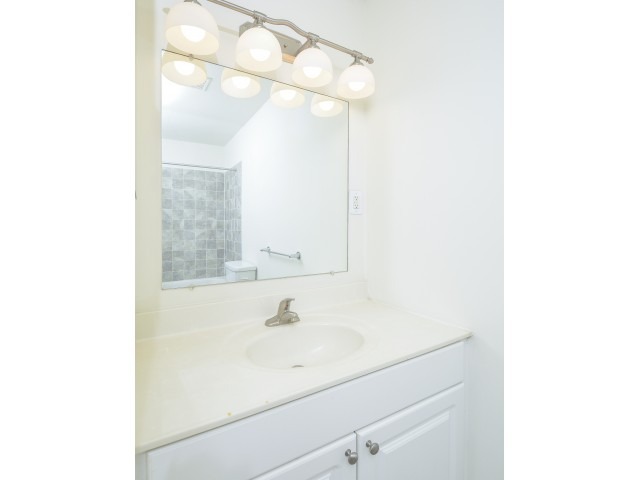 Bathroom with a large mirror, white countertops, and lights.