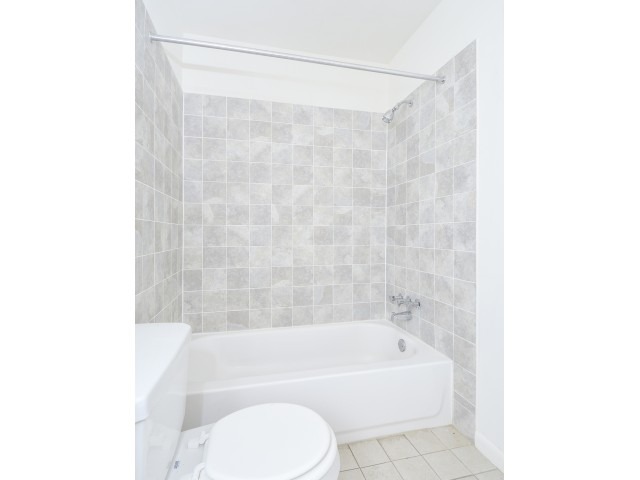Light grey tiles around the bathtub in a bathroom.