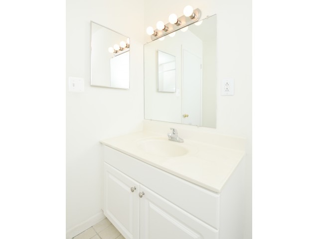 Bathroom with 2 mirrors, vanity lights, and white countertops.