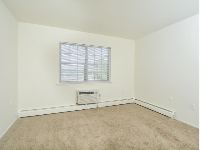 Bedroom with a window and A/C at Woodland Plaza Apartments