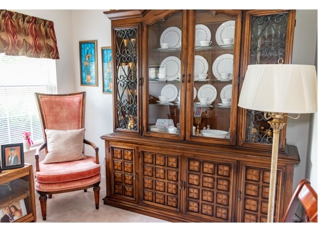 A dining area with carpeting and an armoire with plates at the Upper Deerfield Estates
