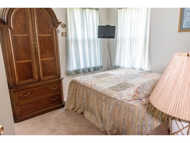 A bedroom with a queen bed and armoire at the Upper Deerfield Estates