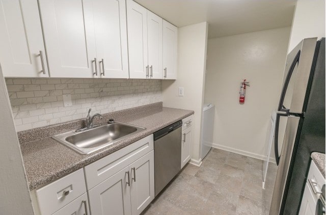 Kitchen area of an apartment, fitted with marble counter space, a sink, tiled flooring, and spacious cabinets