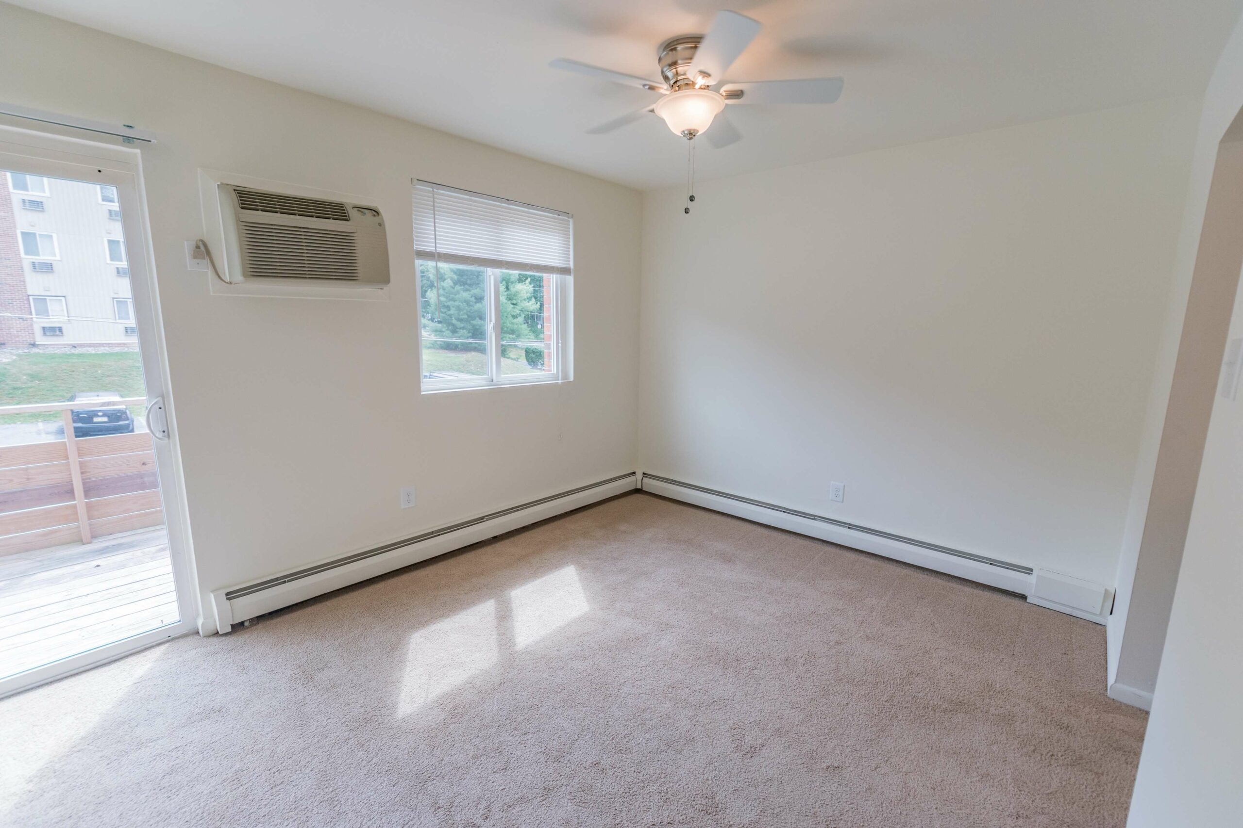 Bedroom area of an apartment unfurnished, fitted with carpet flooring, spacious closet, and a patio access