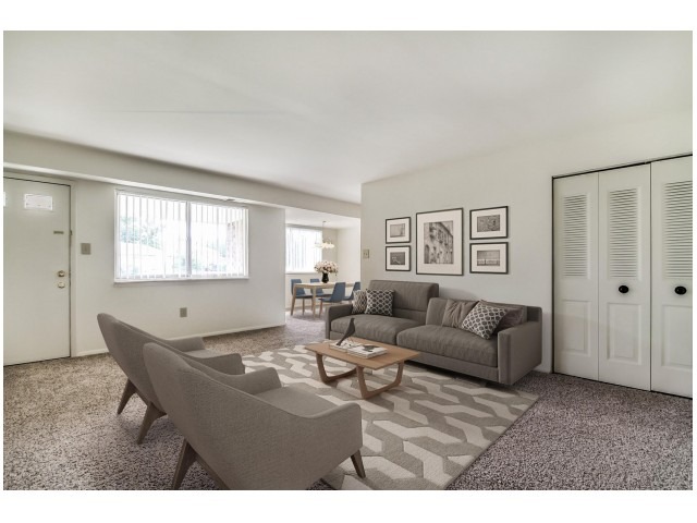 Spacious living area with a coat closet, a sofa, 2 arm chairs, and a coffee table.