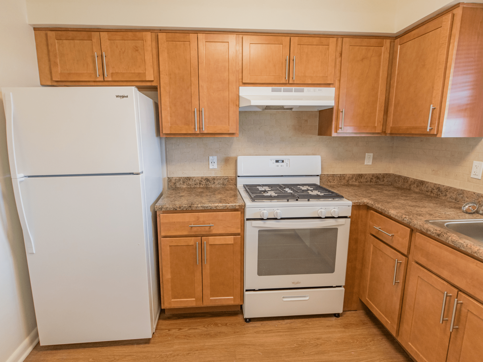 Polo Ridge Apartment's kitchen with brown cabinets and white appliances.