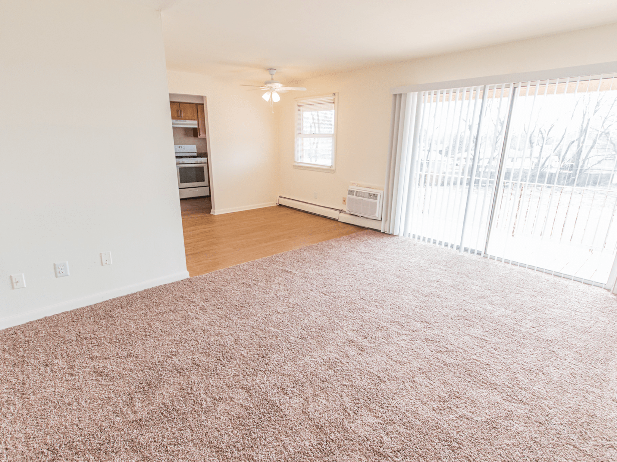 Carpeted floors in living room leading to a balcony at Polo Ridge Apartments