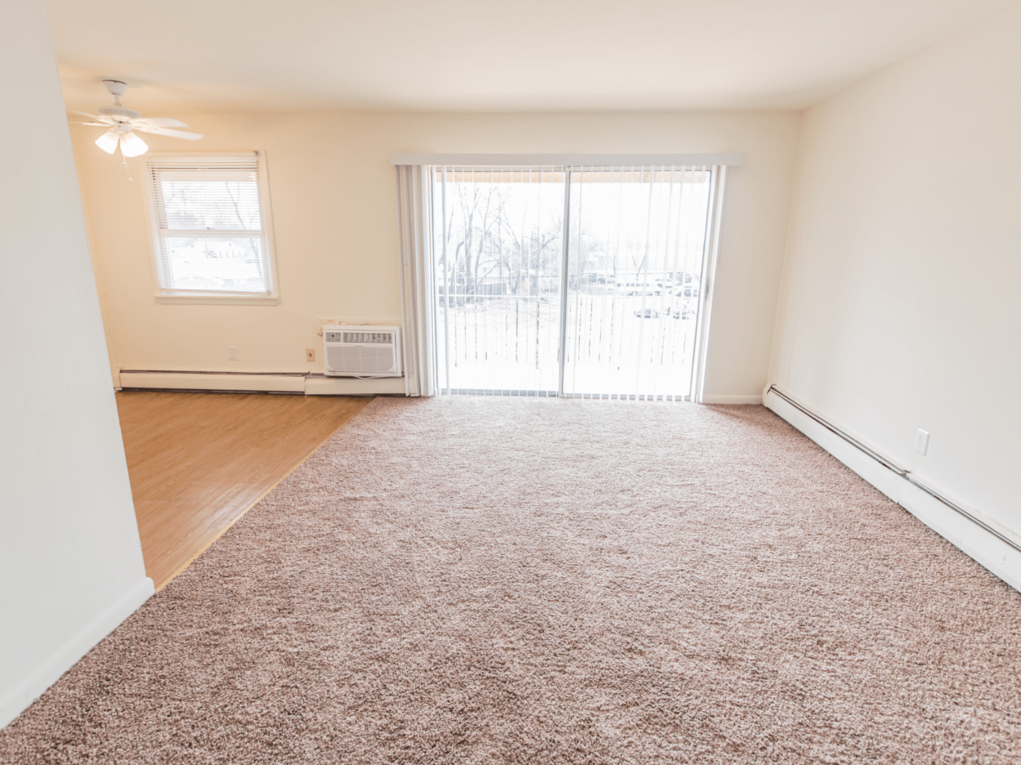 Carpeted living room with a door to the balcony at Polo Ridge Apartments