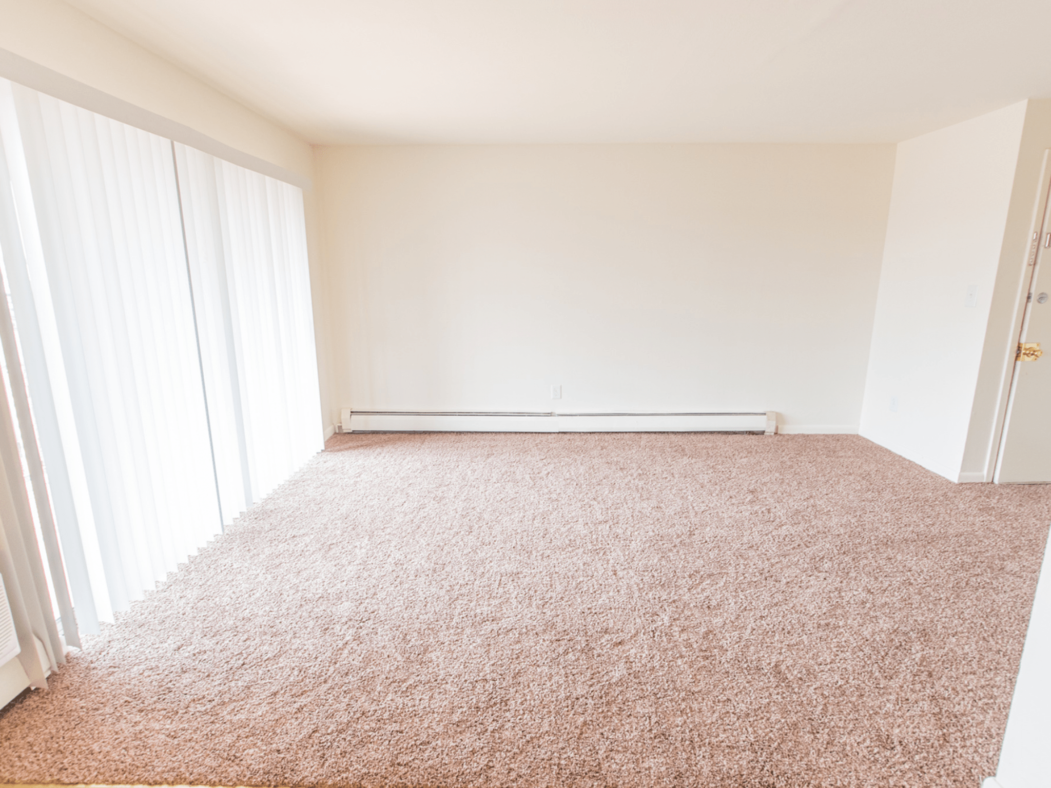 Polo Ridge apartments with carpeted flooring and heating in the living room with sliding doors leading to balcony