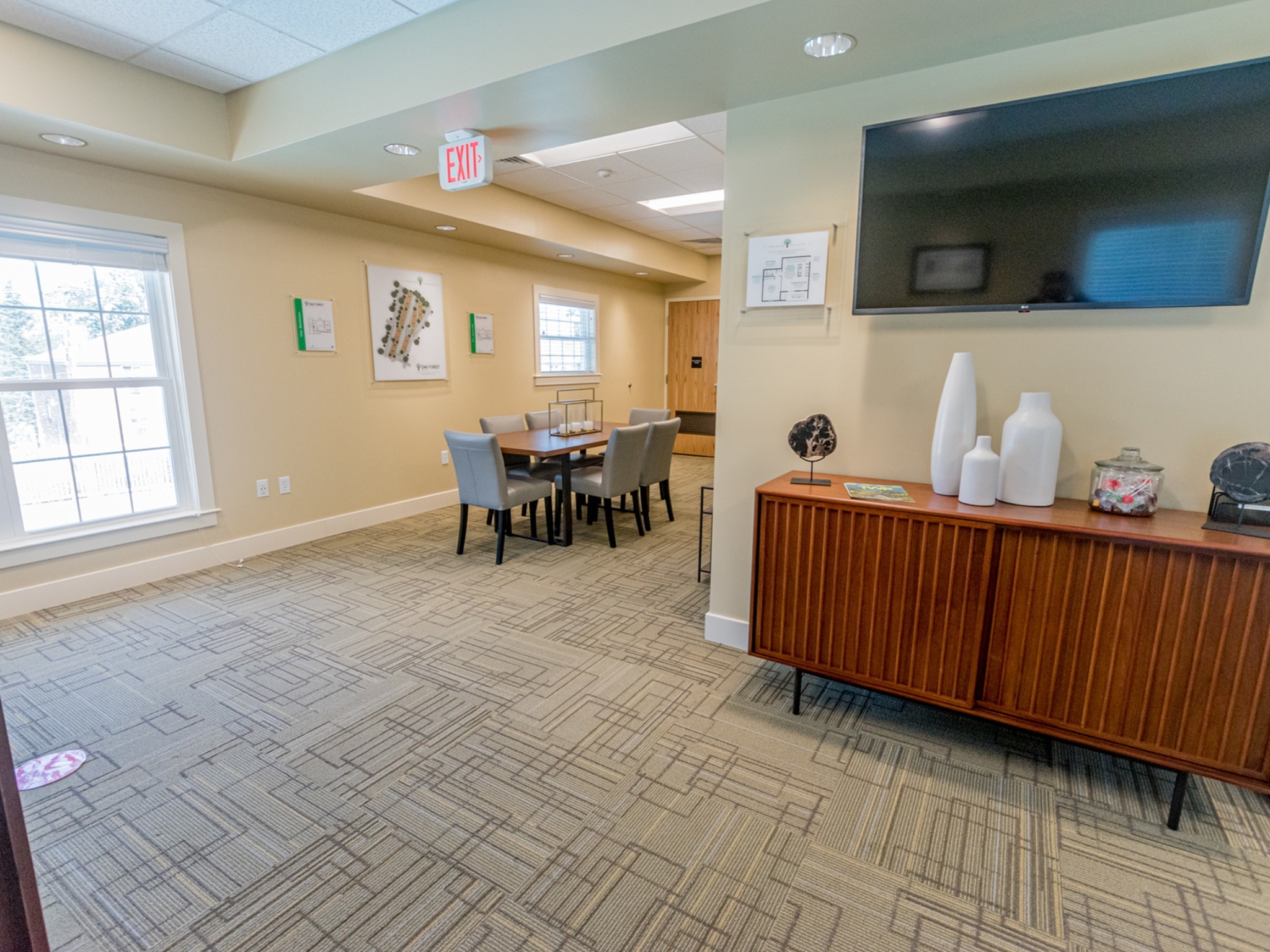 Oak Forest apartments community room area, fitted with a table and chairs, on wall TV, and carpet flooring