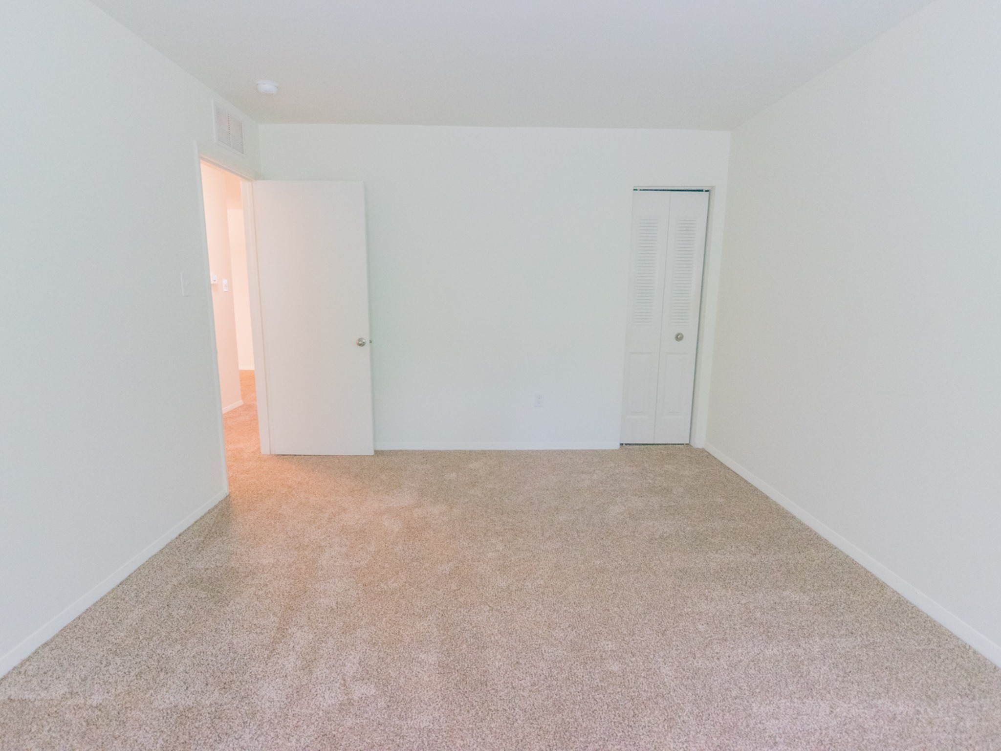 Bedroom with light beige carpets and white walls.
