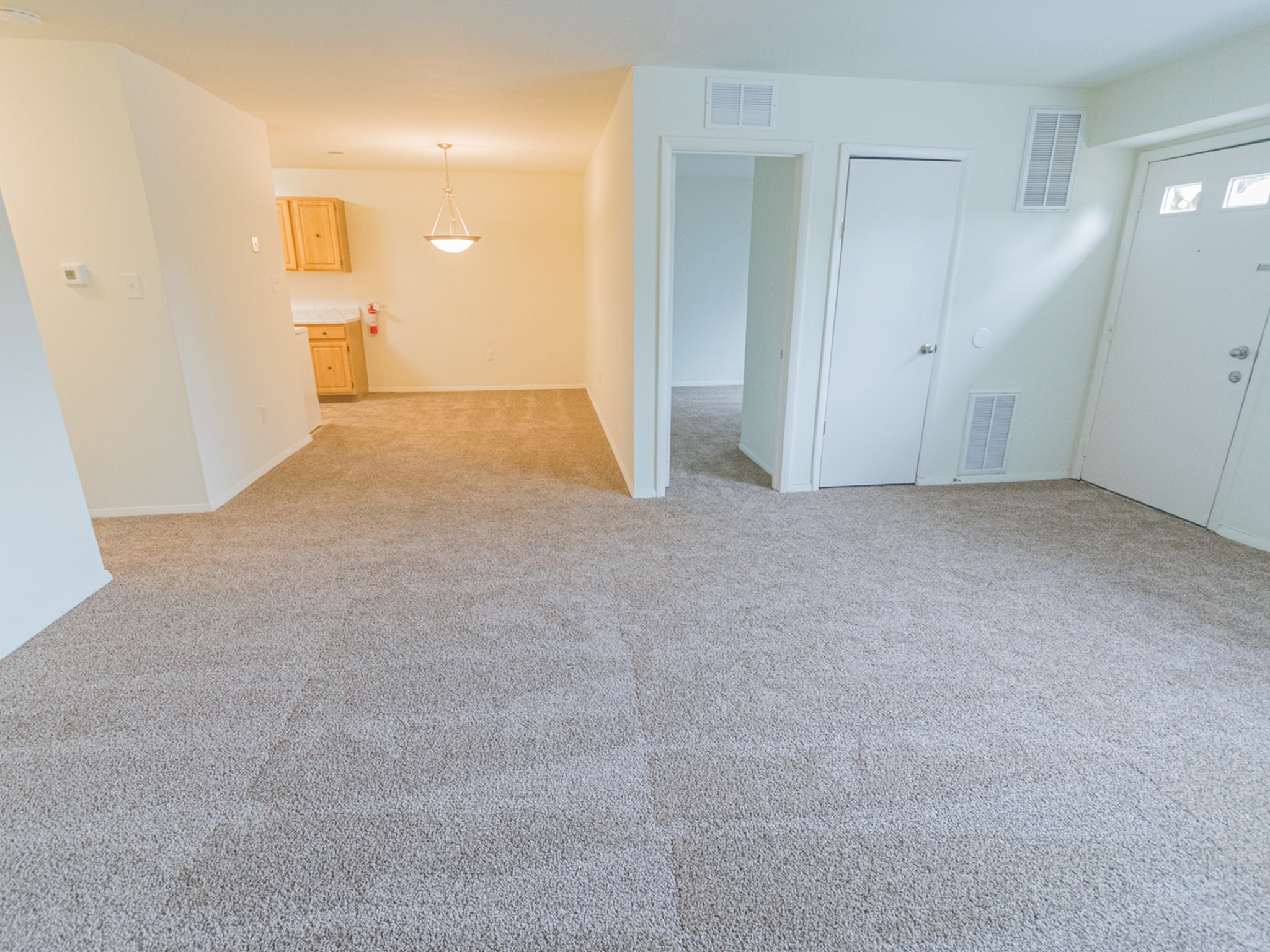Spacious living area with light grey carpets in Indian Run Apartments.