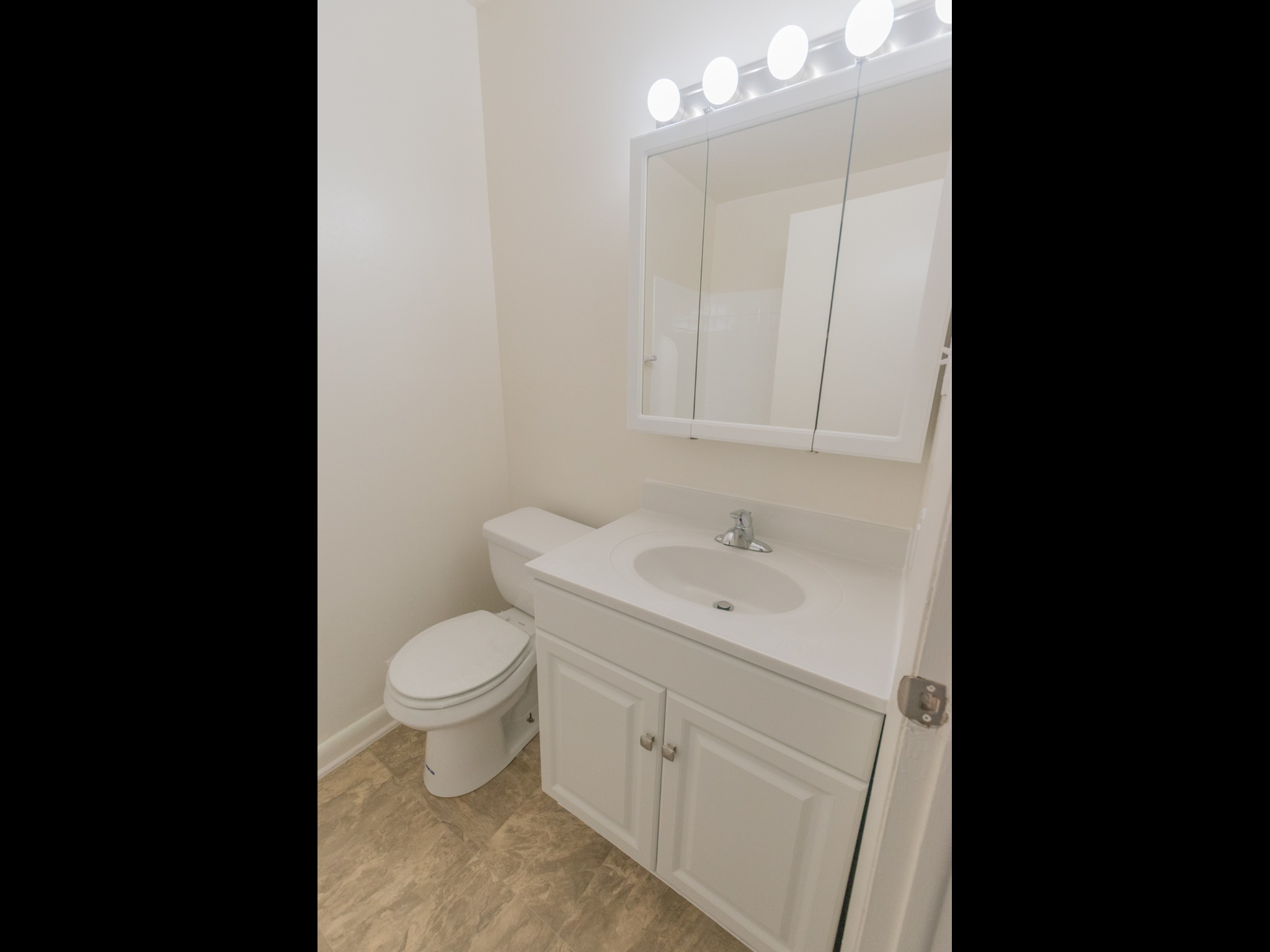 Bathroom with vanity lights, a mirror, a sink, and a toilet.