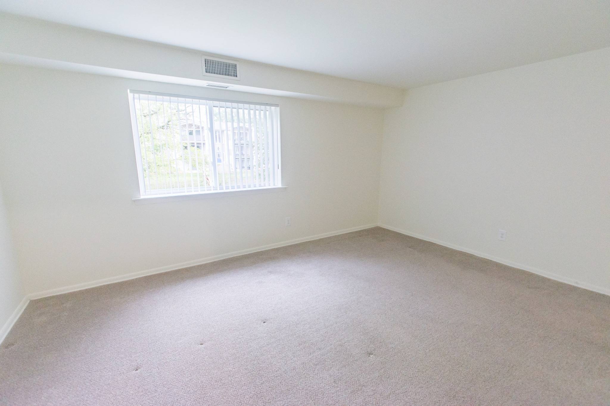 Large bedroom with a window and carpeting at Valley Stream Apartments